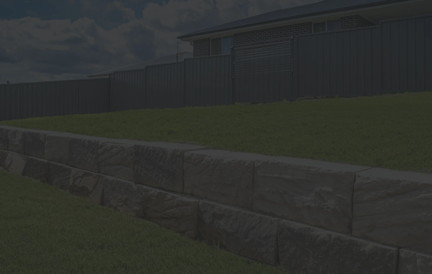 Sandstone block retaining wall stepping along a levelled lawn